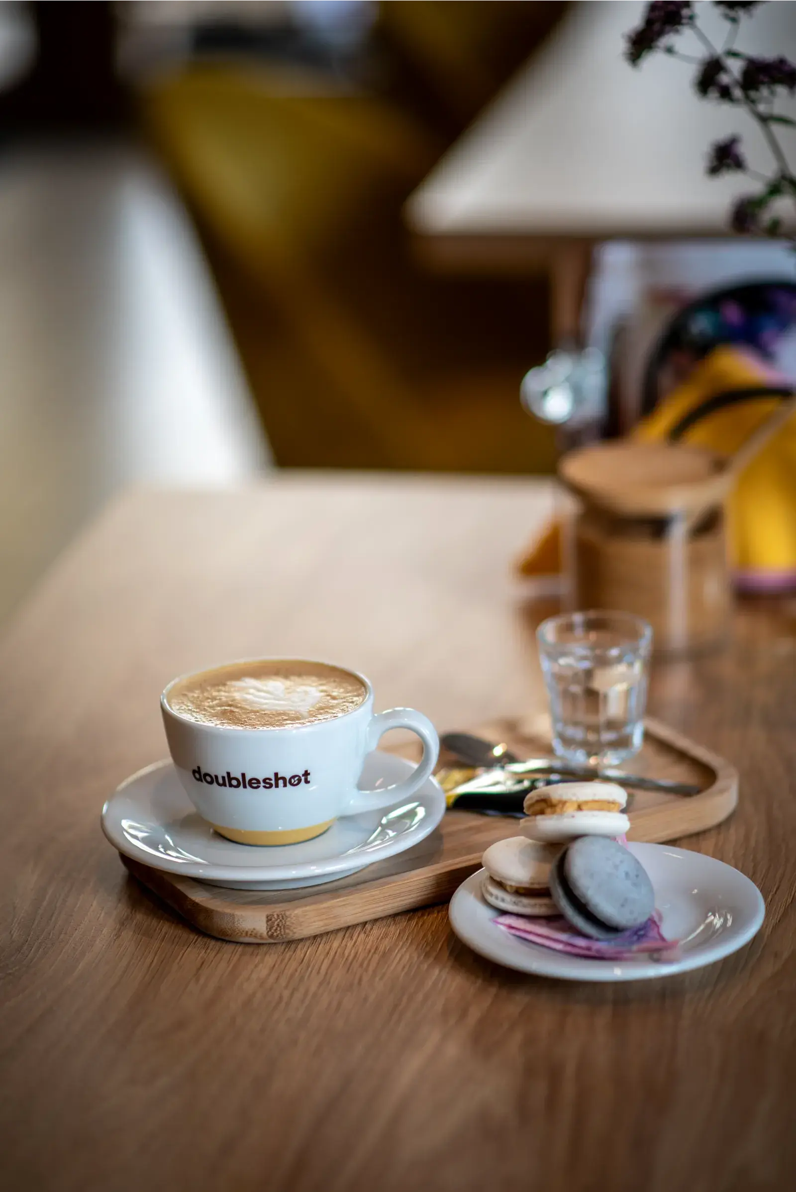 Cappuccino a makronky na dřevěném tácu v kavárně Zrnko v hrnku